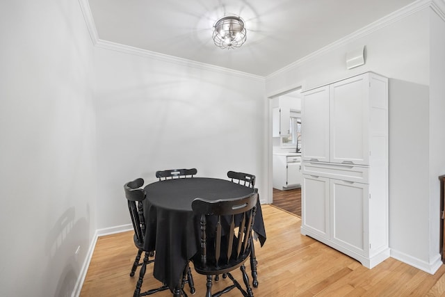 dining space featuring light wood-style floors, ornamental molding, and baseboards