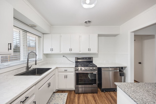 kitchen with dark wood-style flooring, a sink, white cabinets, ornamental molding, and appliances with stainless steel finishes