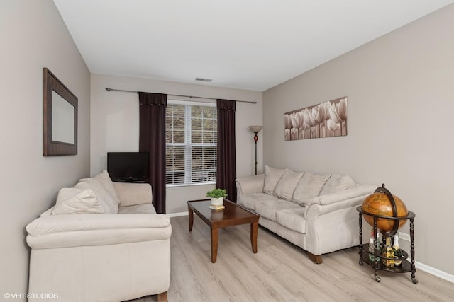 living area with baseboards and light wood finished floors