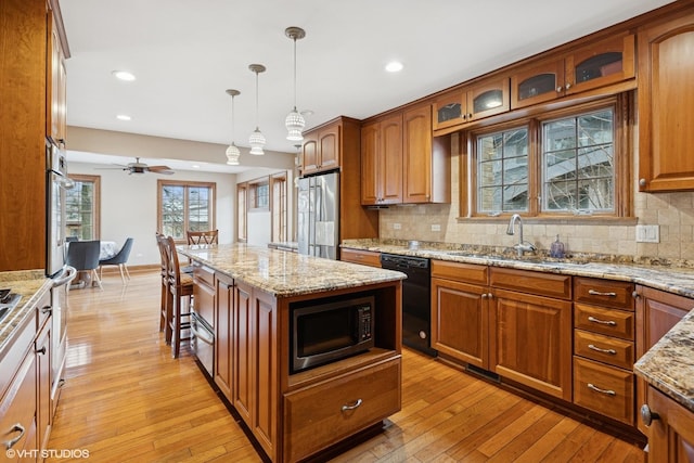 kitchen featuring brown cabinets, light wood-style floors, stainless steel appliances, and a sink