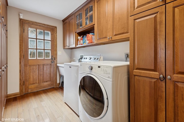 clothes washing area featuring cabinet space, baseboards, light wood-style floors, and washer and dryer