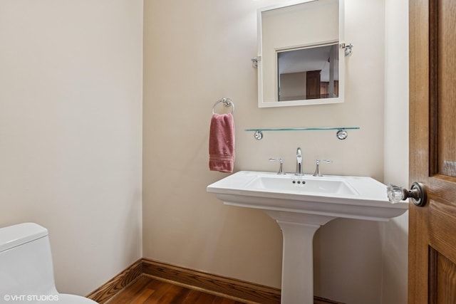 bathroom with toilet, baseboards, and wood finished floors