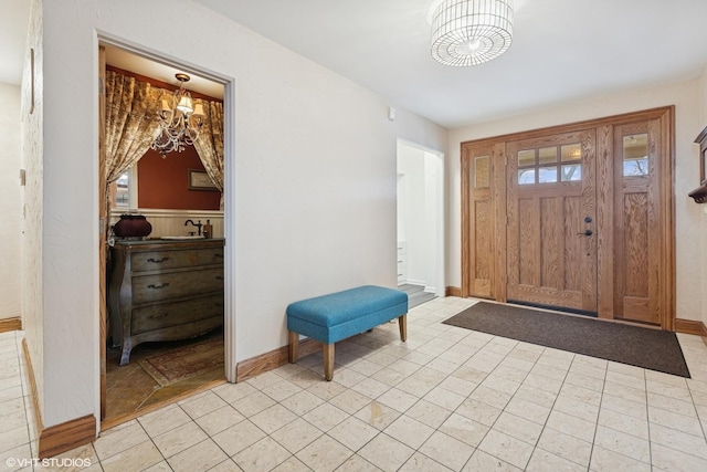 entryway with light tile patterned flooring, a notable chandelier, and baseboards