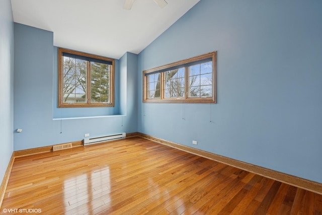 empty room featuring a baseboard radiator, baseboards, vaulted ceiling, and light wood-style flooring