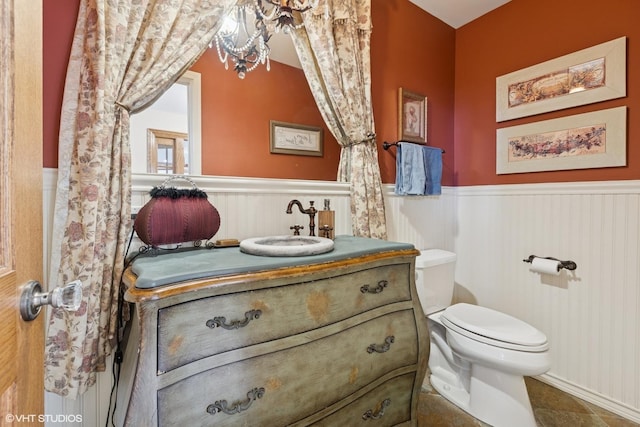 half bath featuring a wainscoted wall, vanity, and toilet