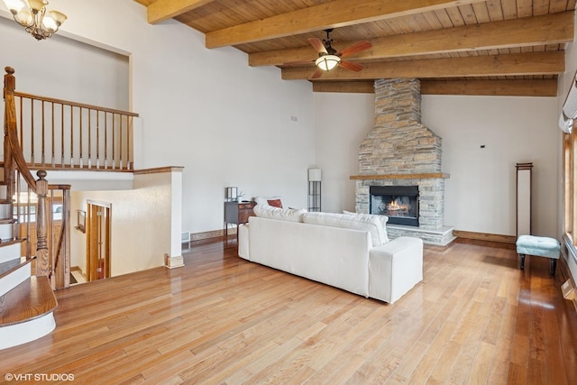 living room with stairway, a stone fireplace, wood finished floors, wooden ceiling, and ceiling fan with notable chandelier