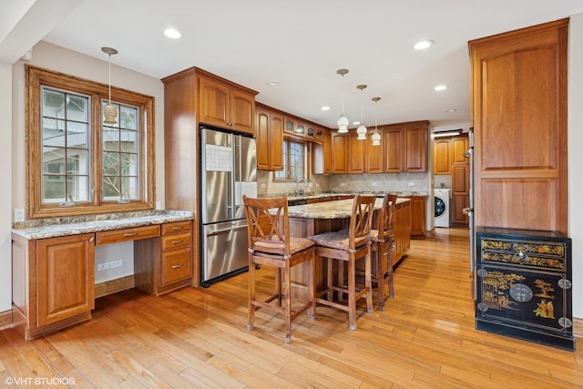 kitchen featuring washer / clothes dryer, high end refrigerator, built in study area, and brown cabinets