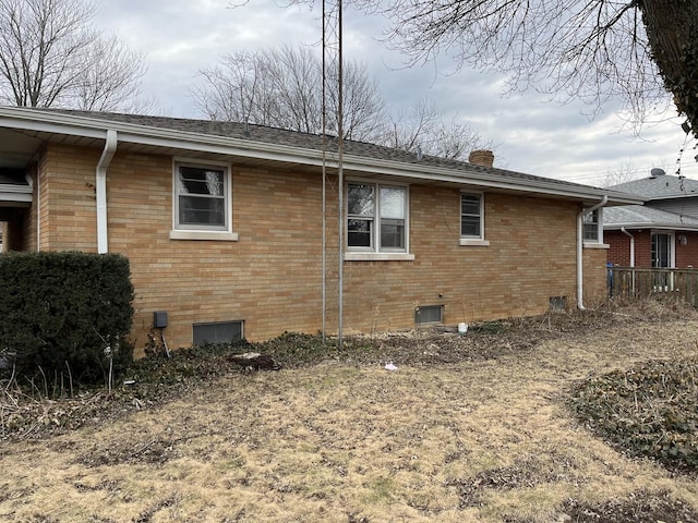 view of property exterior with brick siding and a chimney