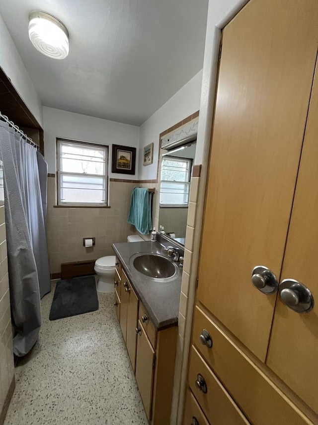 bathroom with a wealth of natural light, a shower with shower curtain, tile walls, and vanity