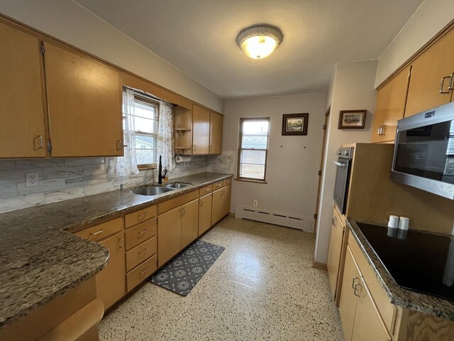 kitchen featuring a healthy amount of sunlight, a baseboard heating unit, stainless steel appliances, and a sink