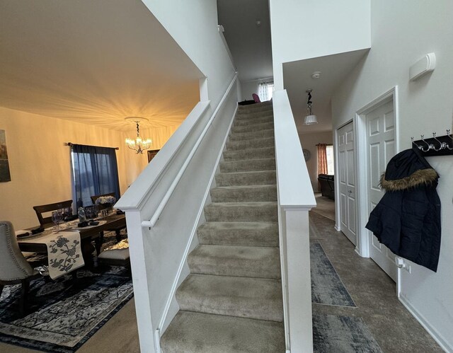 stairway featuring baseboards, a towering ceiling, and a chandelier