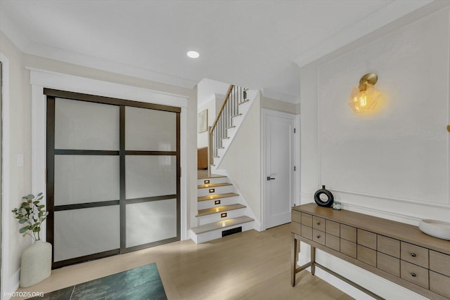 foyer entrance with stairway, wood finished floors, and recessed lighting