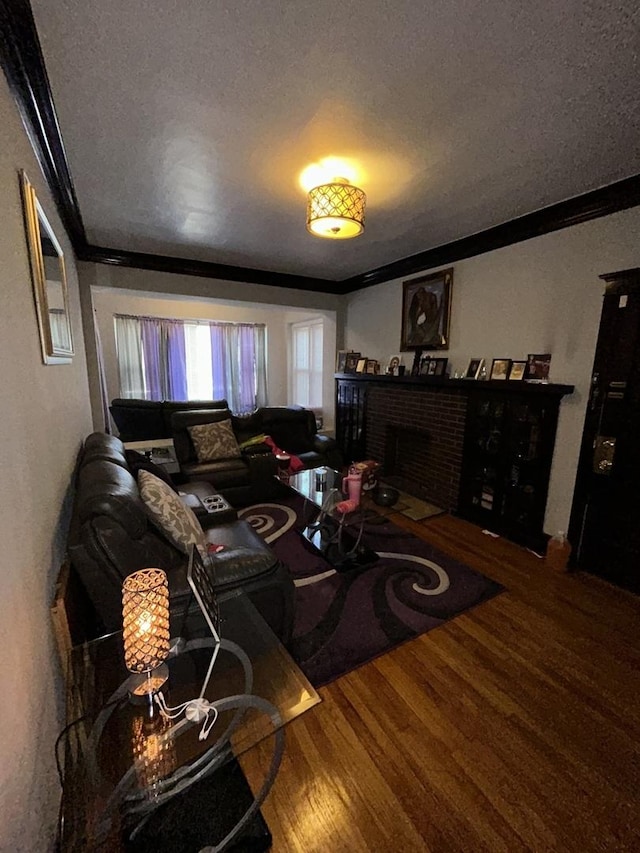 living area with a textured ceiling, a fireplace, ornamental molding, and wood finished floors