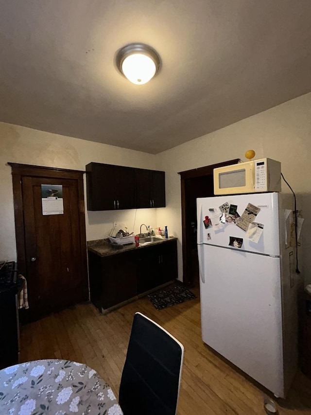 kitchen with a sink, white appliances, and light wood-style floors