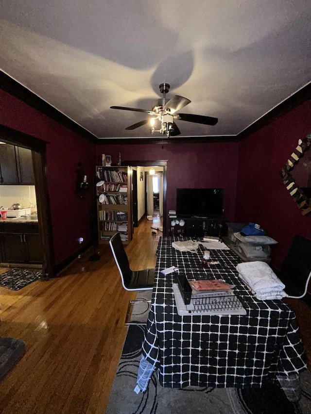 interior space featuring a ceiling fan, ornamental molding, and wood finished floors