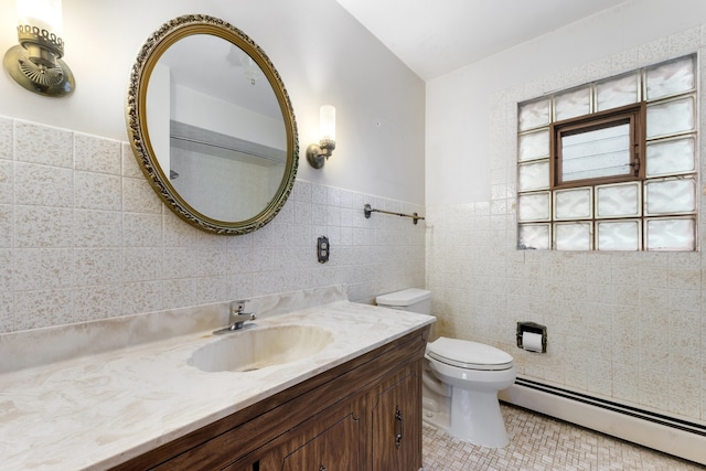 bathroom with toilet, a wainscoted wall, baseboard heating, vanity, and tile walls