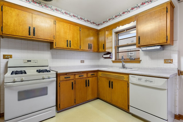 kitchen featuring white appliances, brown cabinets, light countertops, light floors, and a sink