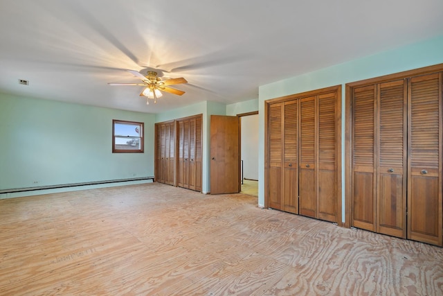 unfurnished bedroom featuring a baseboard radiator, ceiling fan, and multiple closets