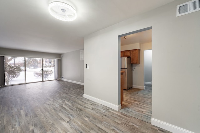 spare room with light wood-style floors, visible vents, and baseboards