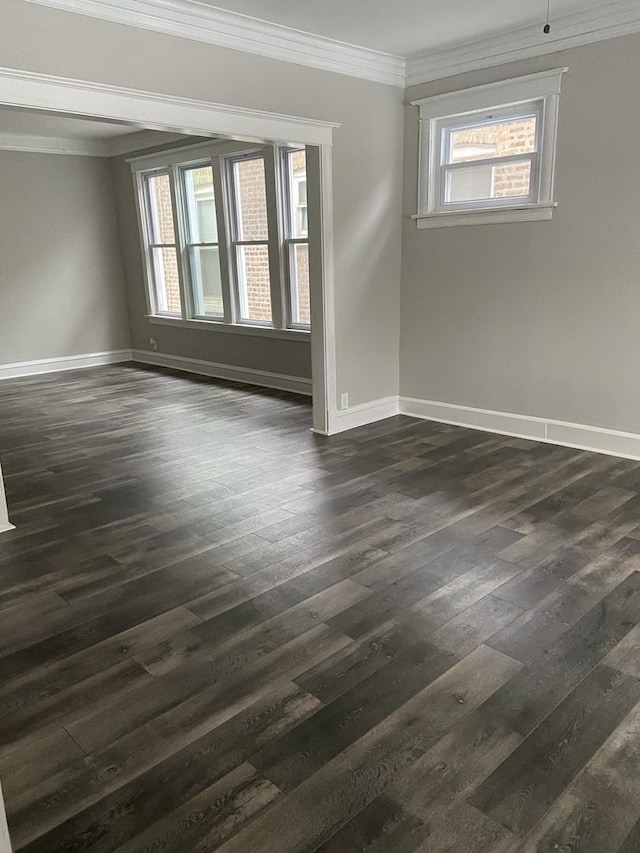 empty room featuring baseboards, dark wood-type flooring, and crown molding