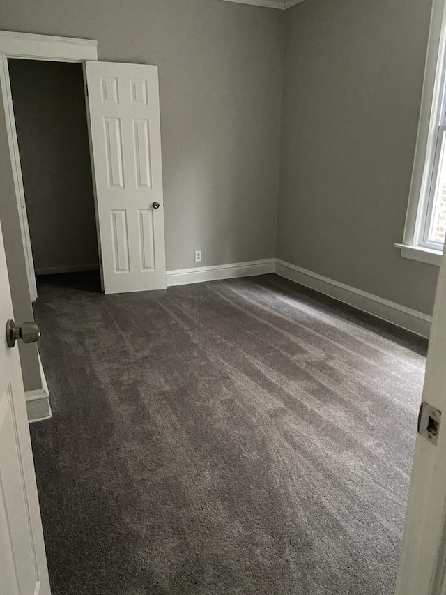 unfurnished bedroom featuring dark colored carpet and baseboards