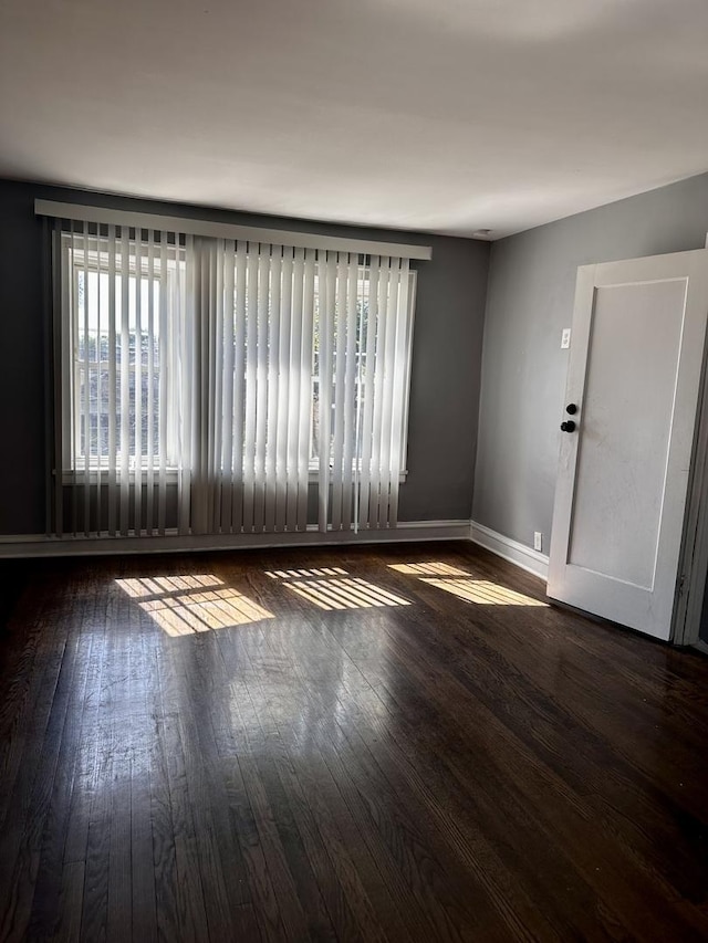 unfurnished room with baseboards and hardwood / wood-style flooring