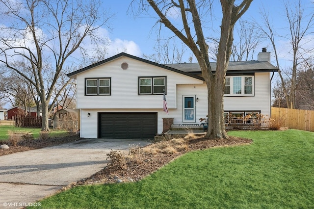 raised ranch with a garage, fence, driveway, a chimney, and a front yard