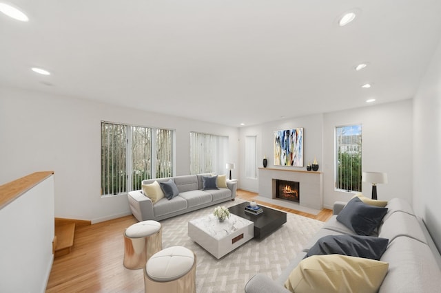 living area featuring a fireplace with flush hearth, recessed lighting, baseboards, and light wood finished floors