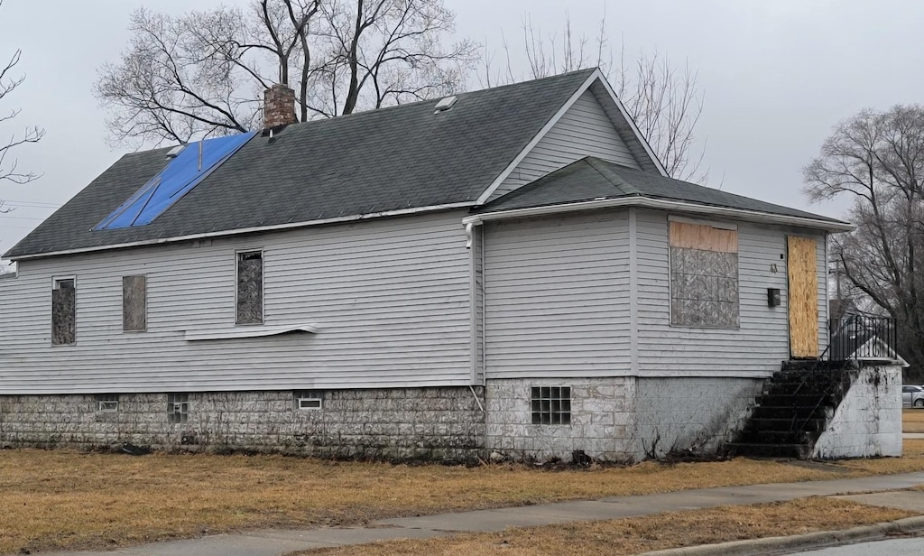 view of side of home featuring roof with shingles and a chimney