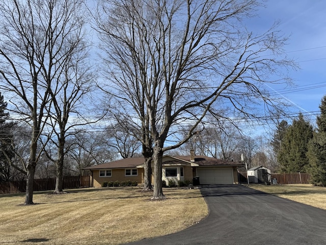 ranch-style house with driveway, an attached garage, a front lawn, and fence