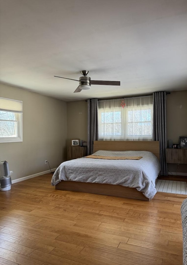 bedroom featuring a ceiling fan, wood finished floors, and baseboards