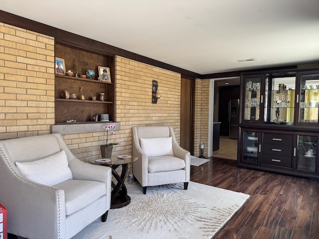 sitting room with dark wood-type flooring, a dry bar, visible vents, and brick wall