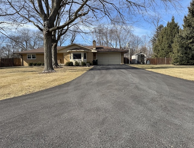 single story home featuring an attached garage, fence, driveway, and a chimney