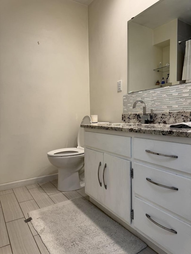 full bath featuring backsplash, toilet, vanity, and baseboards