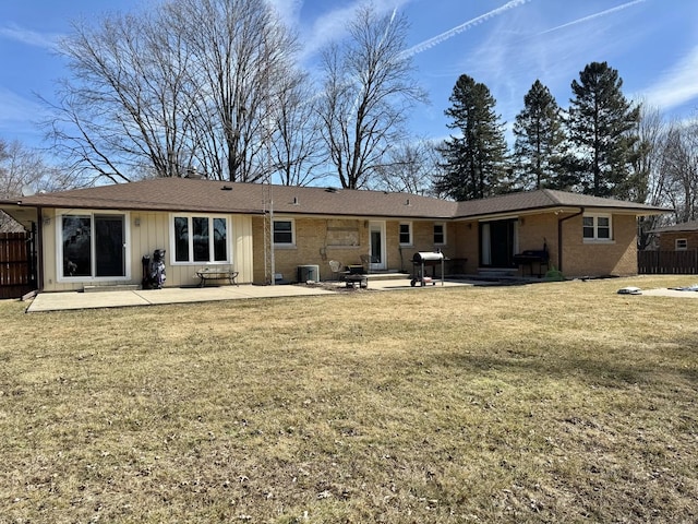 back of house featuring a patio, fence, central air condition unit, a lawn, and brick siding