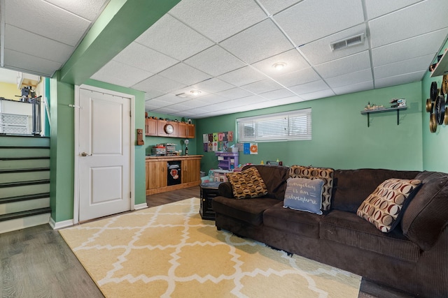 living area with light wood-type flooring, visible vents, a paneled ceiling, and stairs