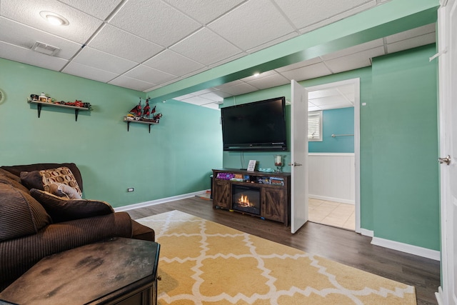 living area with a paneled ceiling, visible vents, wainscoting, wood finished floors, and baseboards