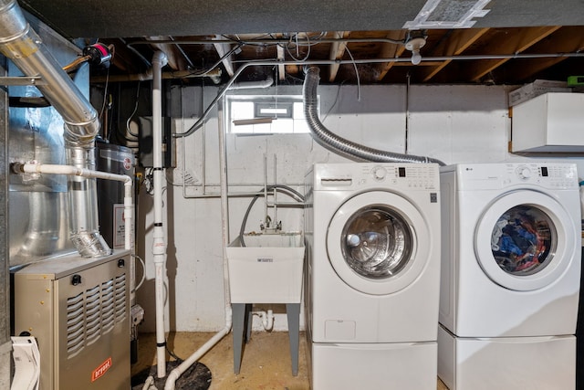 washroom with heating unit, laundry area, a sink, and independent washer and dryer