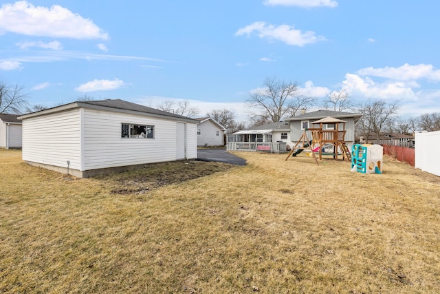 view of yard featuring a playground, fence, and an outdoor structure