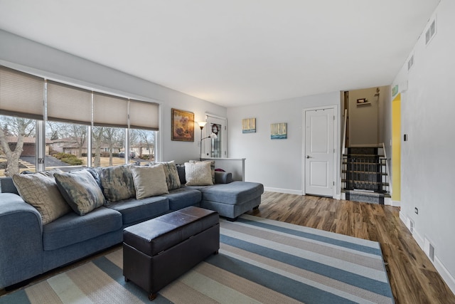 living area featuring visible vents, stairs, baseboards, and wood finished floors