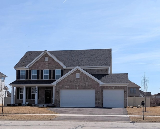 view of front facade with brick siding, fence, a garage, and driveway