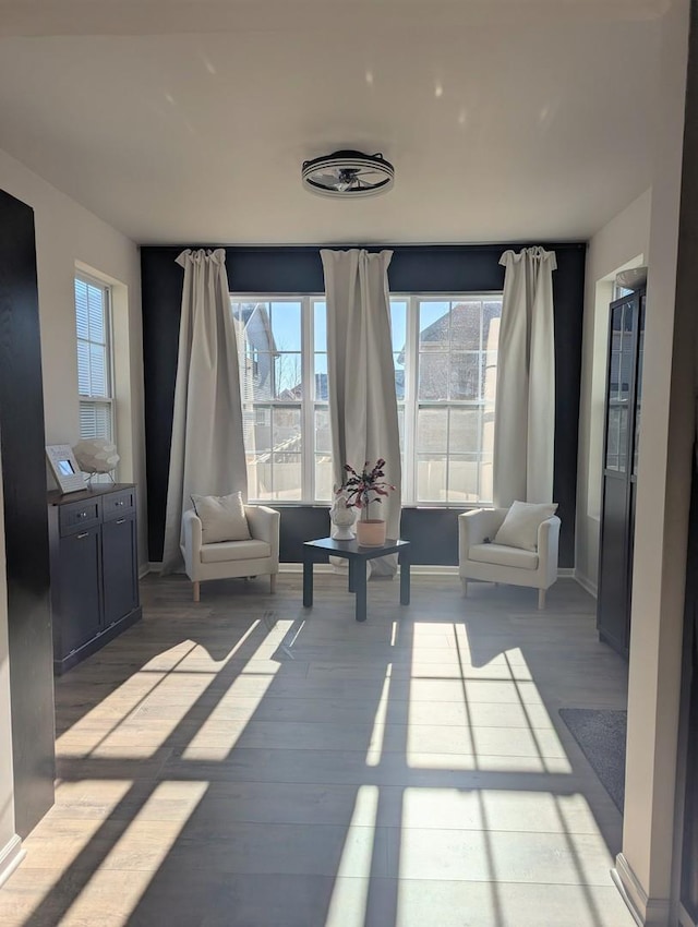 living area with baseboards, light wood-style floors, and a healthy amount of sunlight