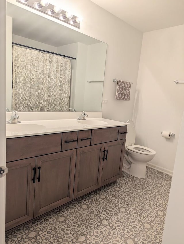 full bathroom with double vanity, toilet, baseboards, and a sink