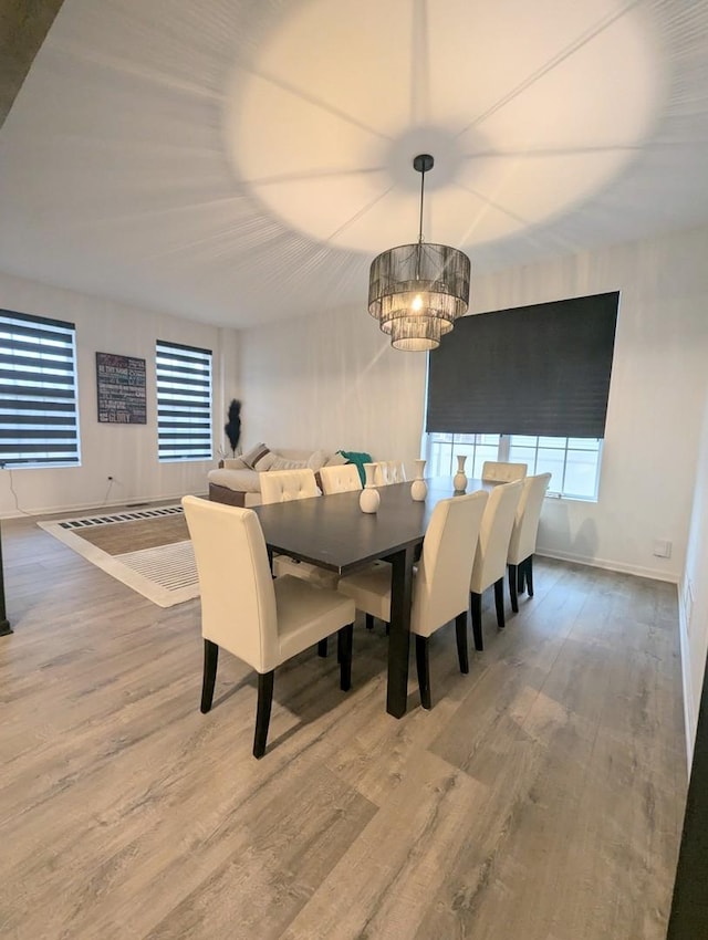 dining space featuring wood finished floors, baseboards, and a chandelier