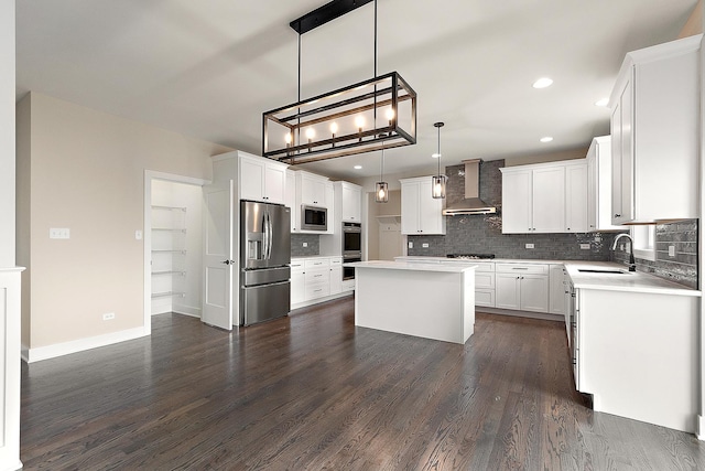 kitchen with stainless steel appliances, a sink, wall chimney range hood, backsplash, and a center island