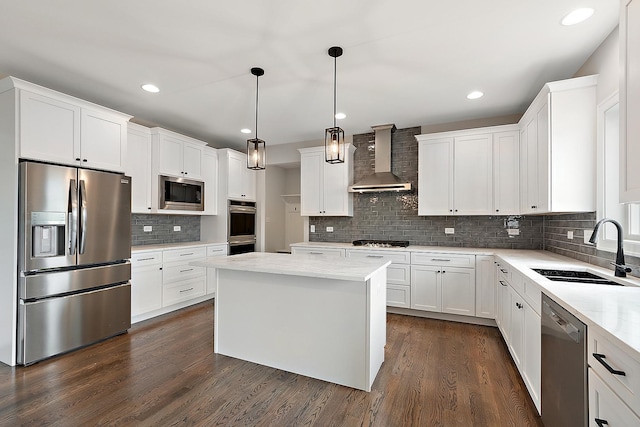 kitchen with dark wood-style floors, stainless steel appliances, white cabinets, a sink, and wall chimney exhaust hood