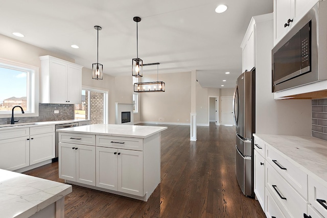 kitchen featuring appliances with stainless steel finishes, dark wood-style flooring, a sink, white cabinetry, and backsplash