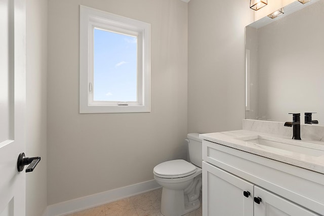 bathroom with vanity, toilet, and baseboards