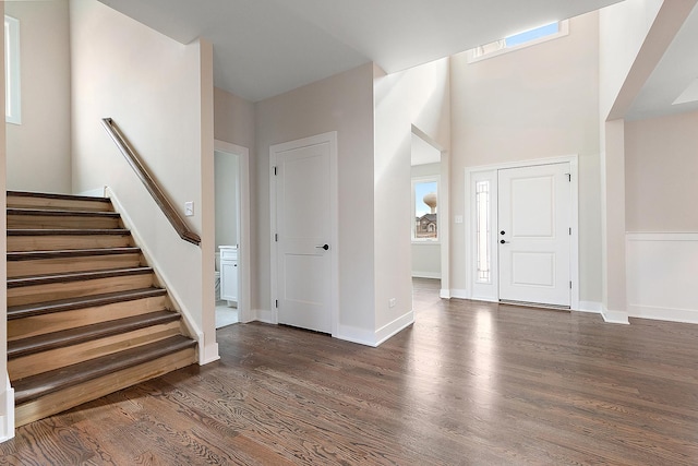 foyer with a towering ceiling, dark wood-style floors, baseboards, and stairway