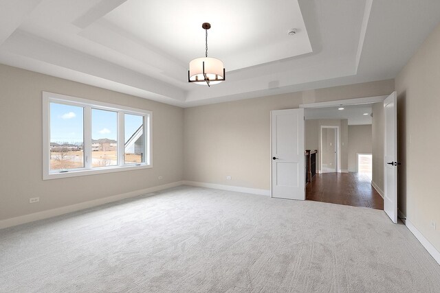 unfurnished room featuring carpet, baseboards, a tray ceiling, and an inviting chandelier